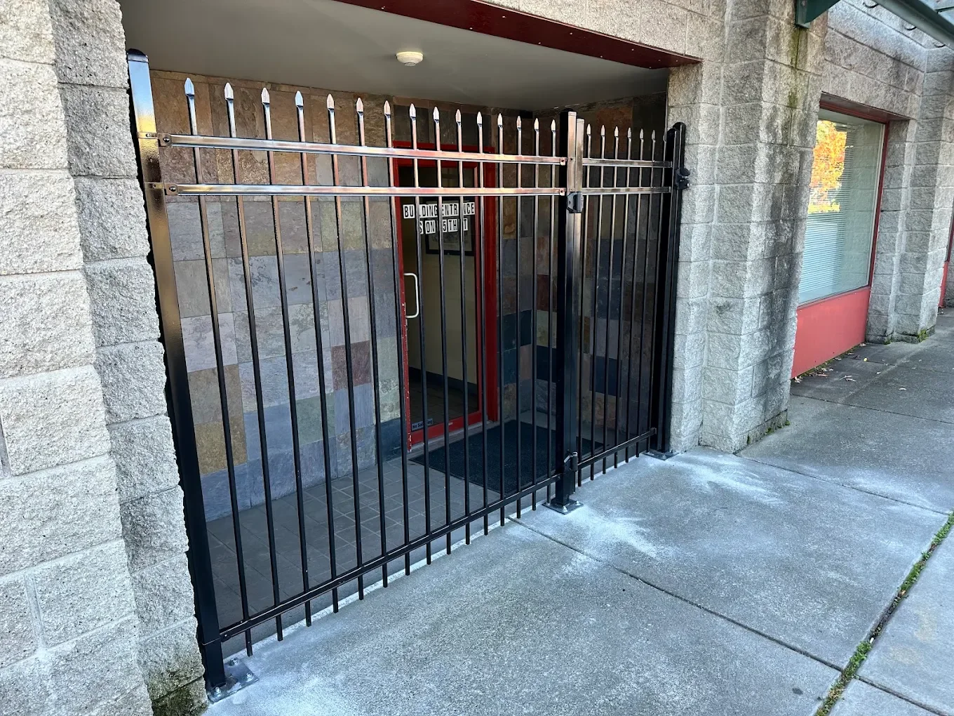 Blue Ribbon black metal fencing and a secure gate across a commercial building entrance.